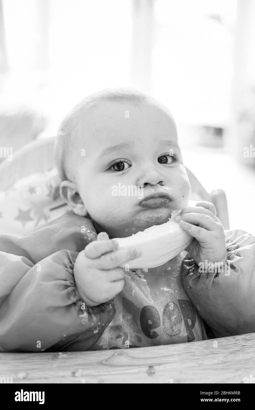 Niedliches Baby, das aus dem Hochstuhl isst Stockfoto