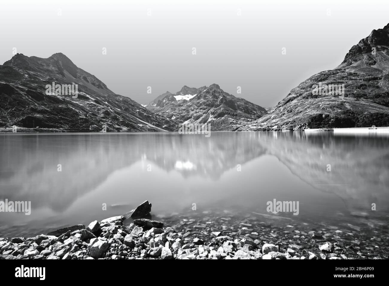 Landschaftlich reizvolle Alpenlandschaft mit See und Bergen. Reflexionen in einem ruhigen Bergsee. Schwarzweiß-, Schwarzweiß-Fotografie. Stockfoto