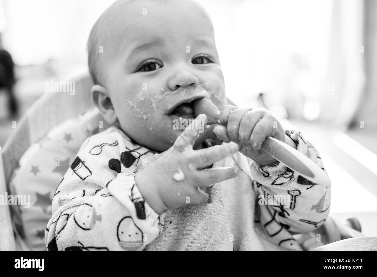 Niedliches Baby, das aus dem Hochstuhl isst Stockfoto