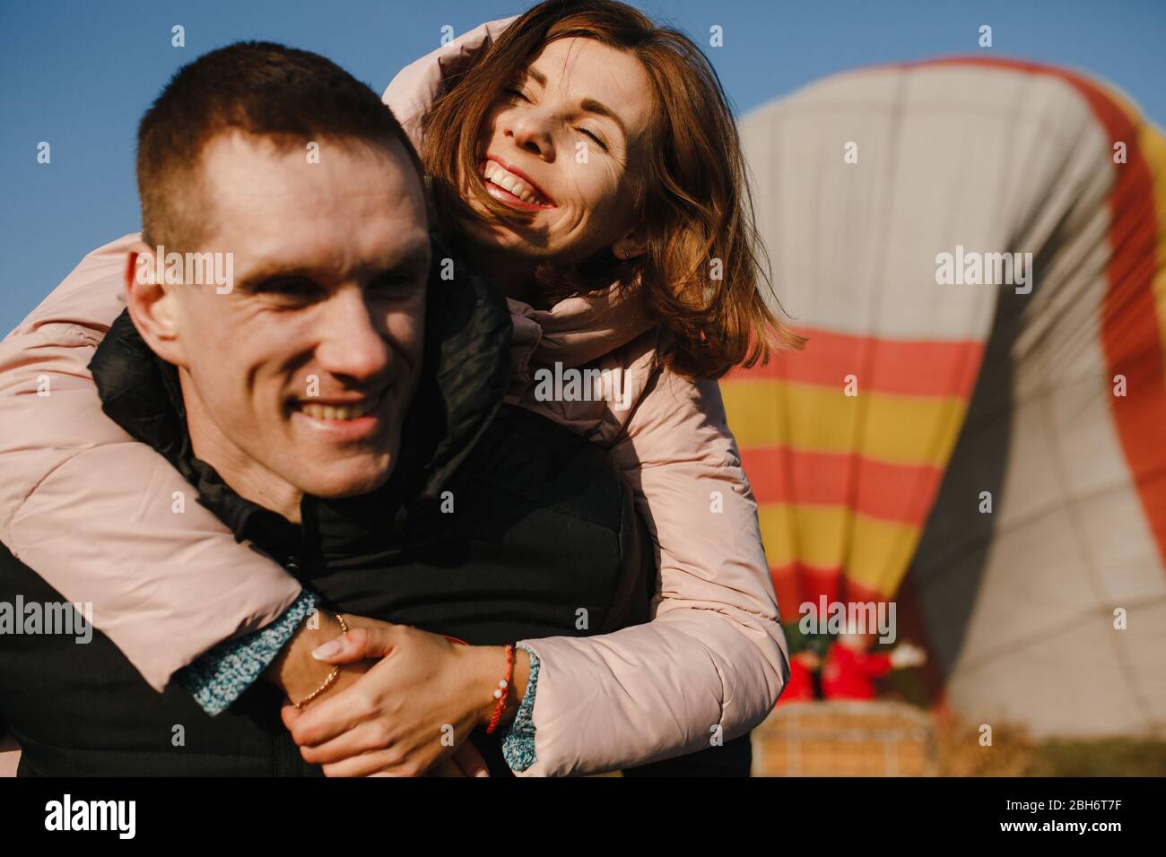 Lächelndes verliebter Paar auf dem Hintergrund des Heißluftballons Stockfoto