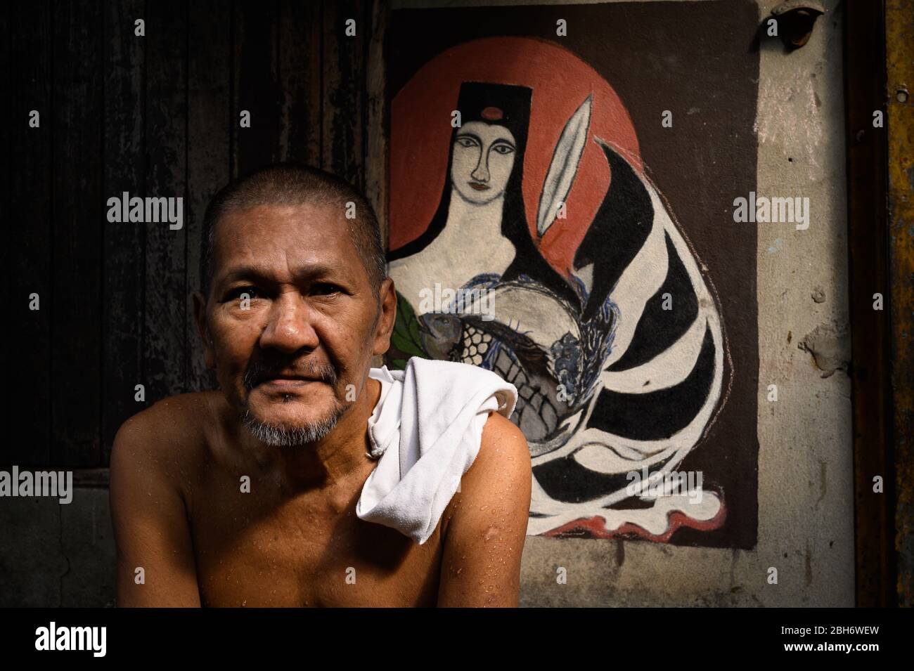 Porträt eines Mannes mittleren Alters vor Kunstwerk, Bangkok, Thailand Stockfoto
