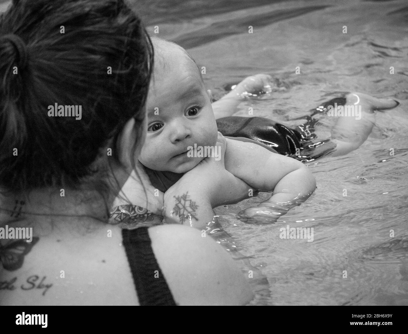 Kleines Baby, das mit der Mutter schwimmen lernt Stockfoto