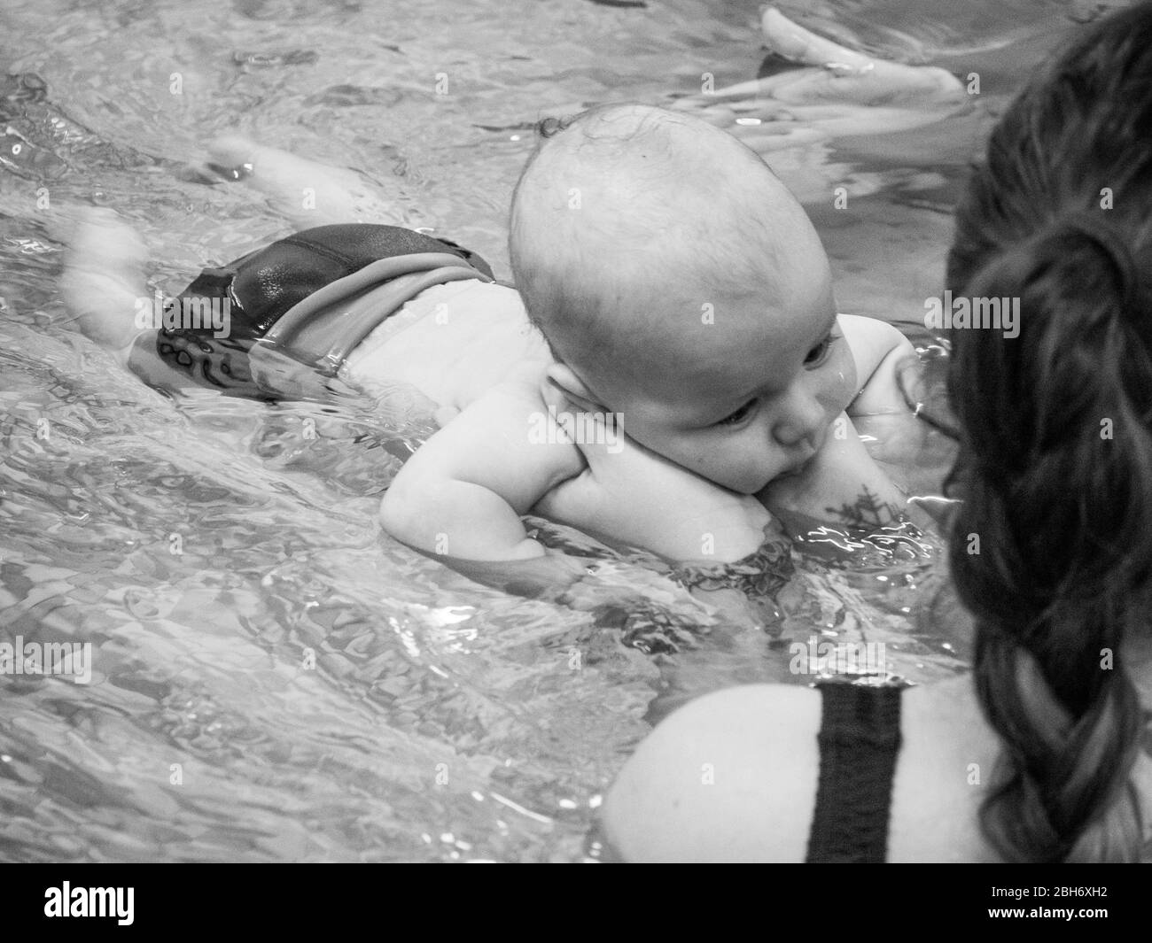 Kleines Baby, das mit der Mutter schwimmen lernt Stockfoto