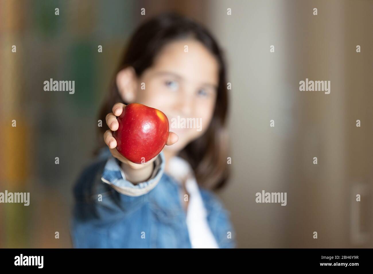 Glückliches Mädchen zeigt einen roten Apfel zu Hause Stockfoto