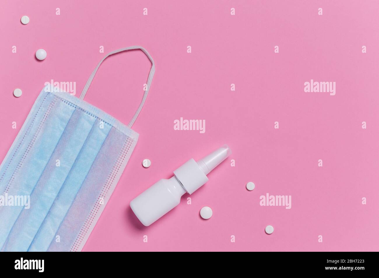 Schutz vor Coronavirus und Allergie. Blaue medizinische OP-Maske, Nasenspray und weiße Pillen auf rosa Hintergrund. Hygienemaßnahmen zu verhindern Stockfoto