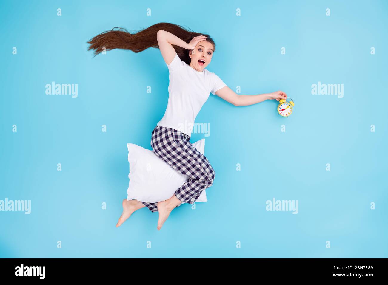 Full size hohen Winkel über flach legen Blick Foto von hübschen Dame liegen Kissen zwischen den Beinen halten Wecker früh aufwachen, nachdem Party tragen T-Shirt Hosen Stockfoto