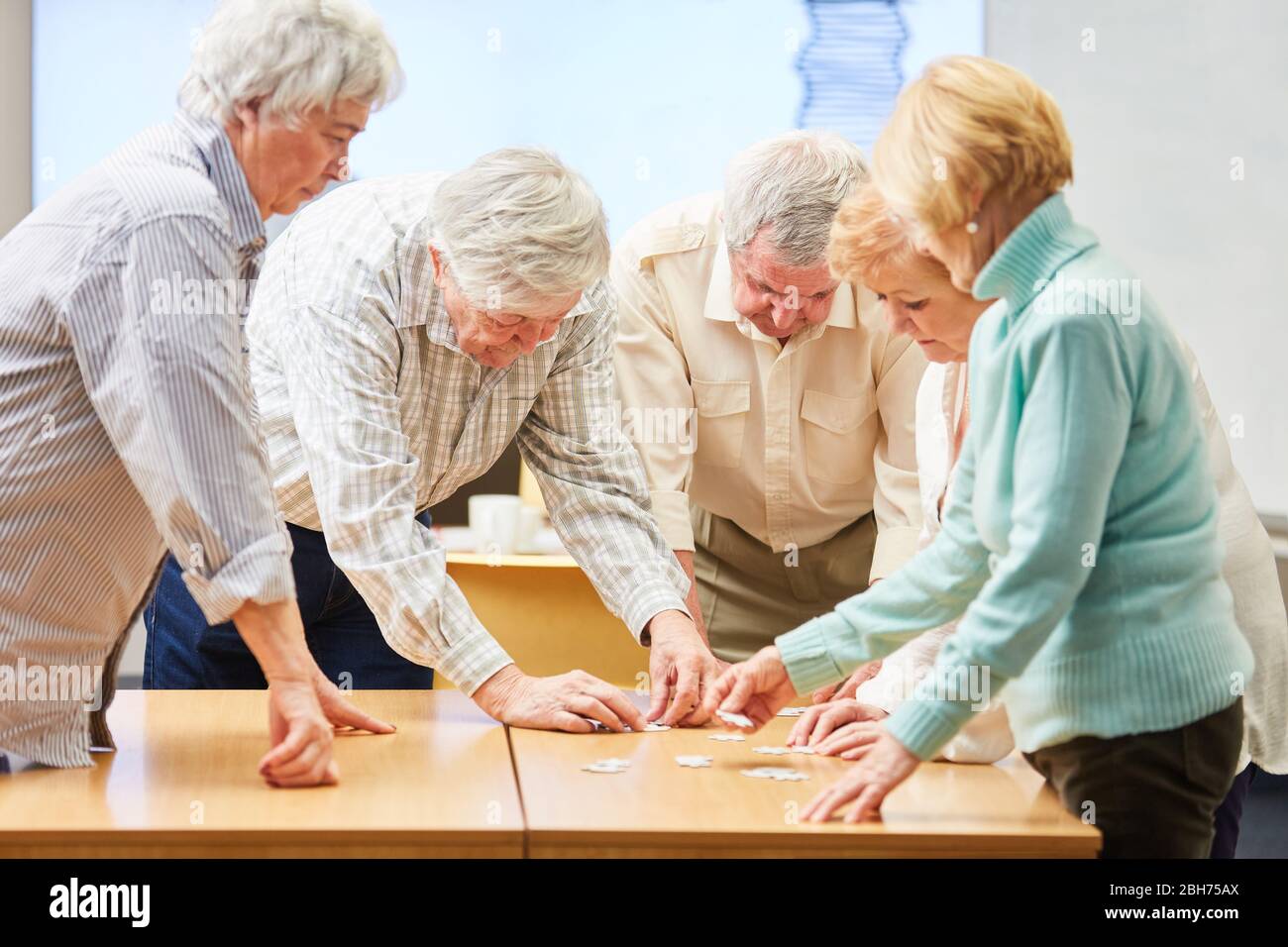 Gruppe von Senioren mit Demenz spielen das Puzzle als Gedächtnistraining in einem Altersheim