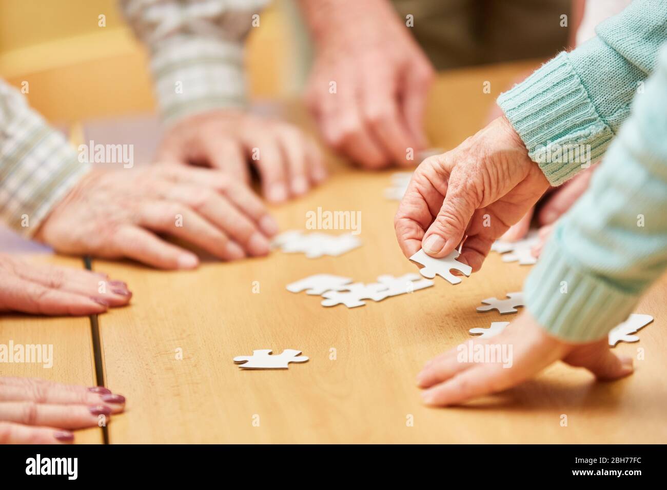 Hand eines älteren Bürgers hält ein Stück des Puzzles, während ein Puzzle in einem Altersheim zu spielen Stockfoto