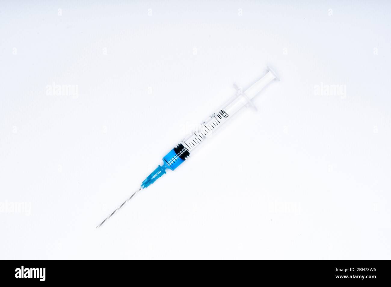 Isolierte Spritze mit blauer Flüssigkeit auf weißem Hintergrund. Medizin und Gesundheitskonzept im Angesicht einer Pandemie oder eines Virus. Stockfoto