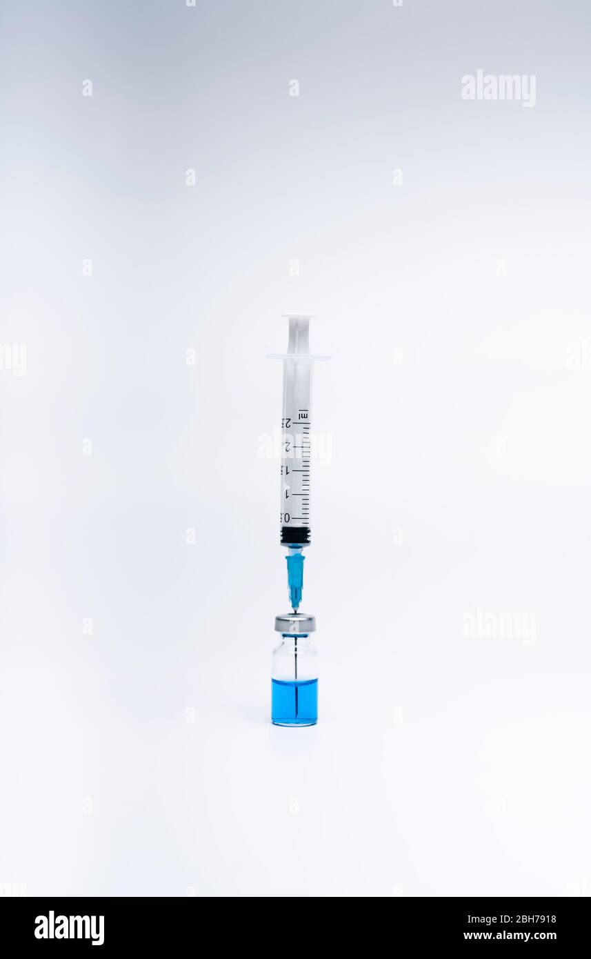 Spritze mit Impfstoff in einer Fläschchen Flasche mit blauer Flüssigkeit auf weißem Hintergrund. Medizin und Gesundheitskonzept im Angesicht einer Pandemie oder eines Virus. Stockfoto