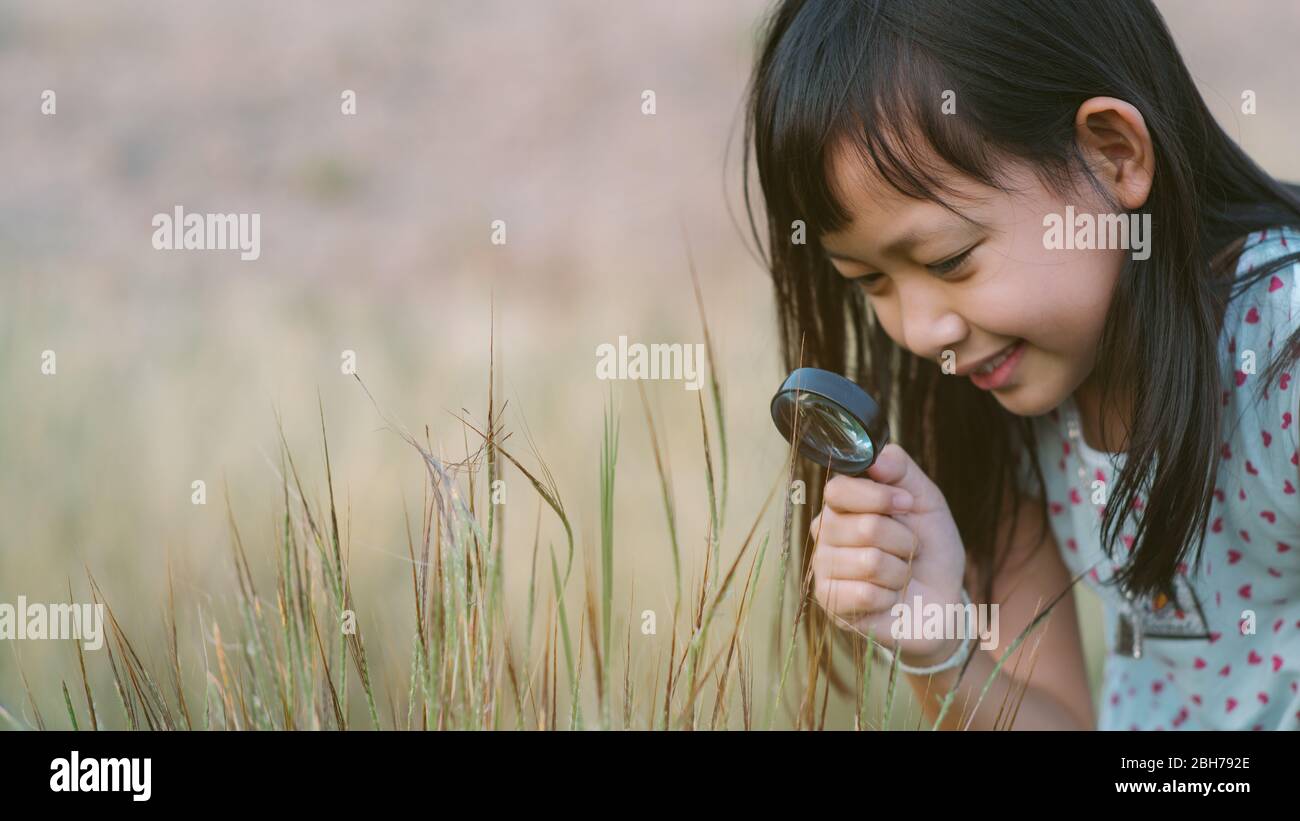 Glücklich asiatische Kind Mädchen erkunden Natur mit Lupe.16:9 Stil Stockfoto