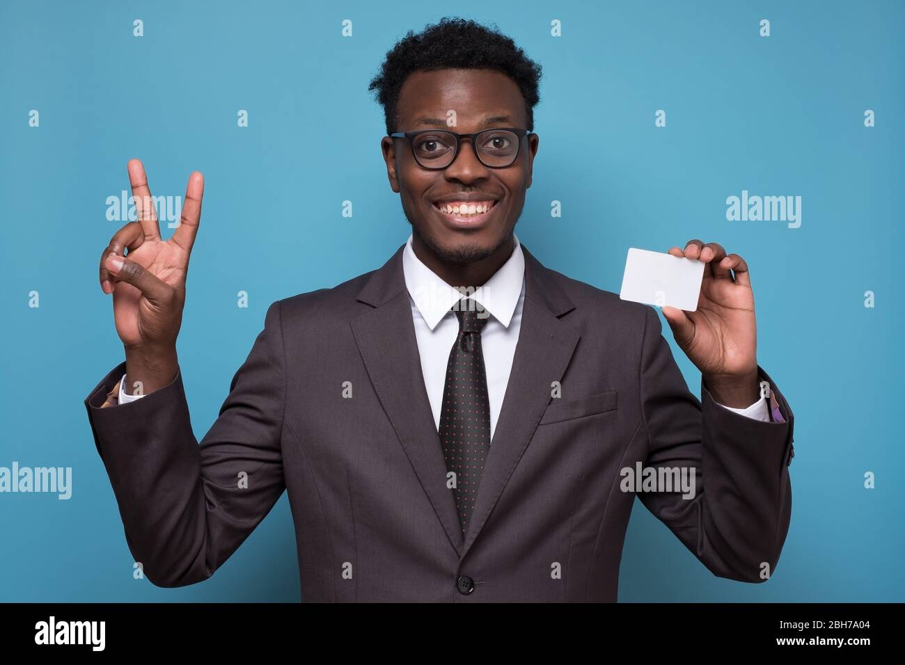 Junger afroamerikanischer Mann in Anzug zeigt zwei Finger halten Kreditkarte. Stockfoto