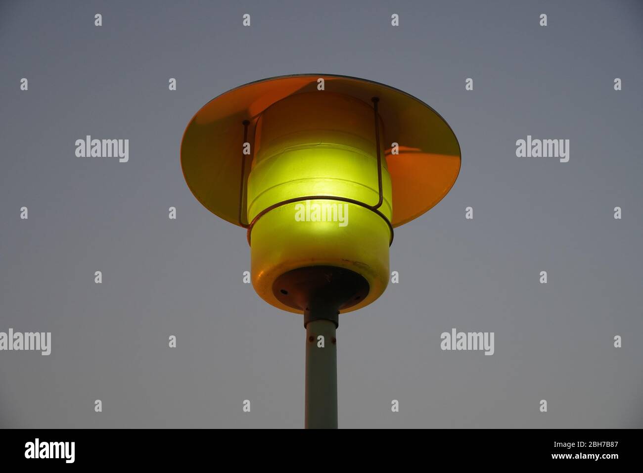 Street Lamp Post mit Blick auf die Skyline am Abend. Außenbeleuchtung mit Himmel Hintergrund. Eine einzige Straßenbeleuchtung mit Kapuze. Stockfoto