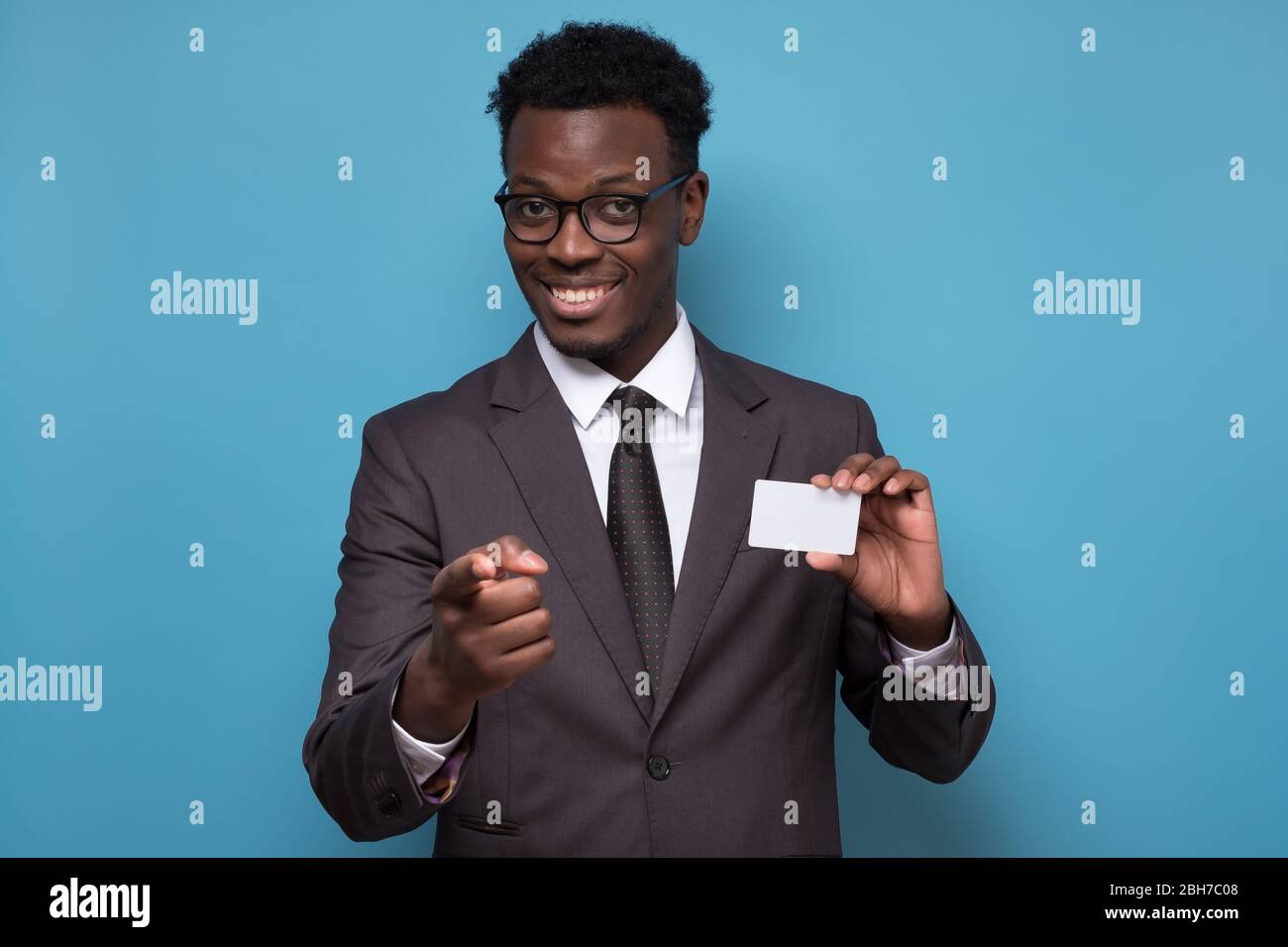 Junger afroamerikanischer Mann in Anzug mit Kreditkarte zeigt auf Sie. Stockfoto