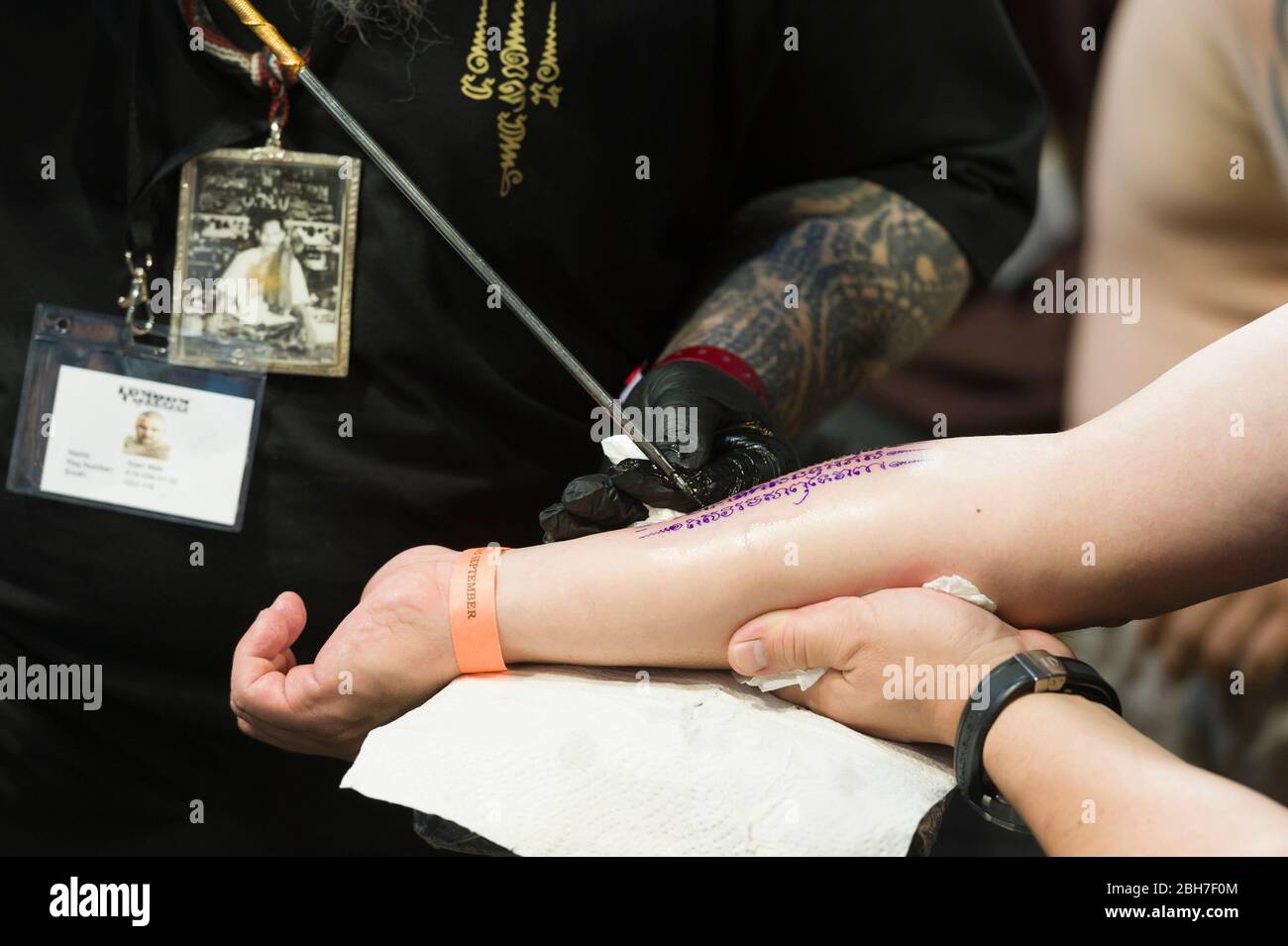 Ein Mann, der auf der 12. London Tattoo Convention 2016, Tobacco Dock, 50 Porter, ein Arm-Tattoo von einem Tätowierer mit der Metall-Tube-Tätowierungstechnik bekommt Stockfoto