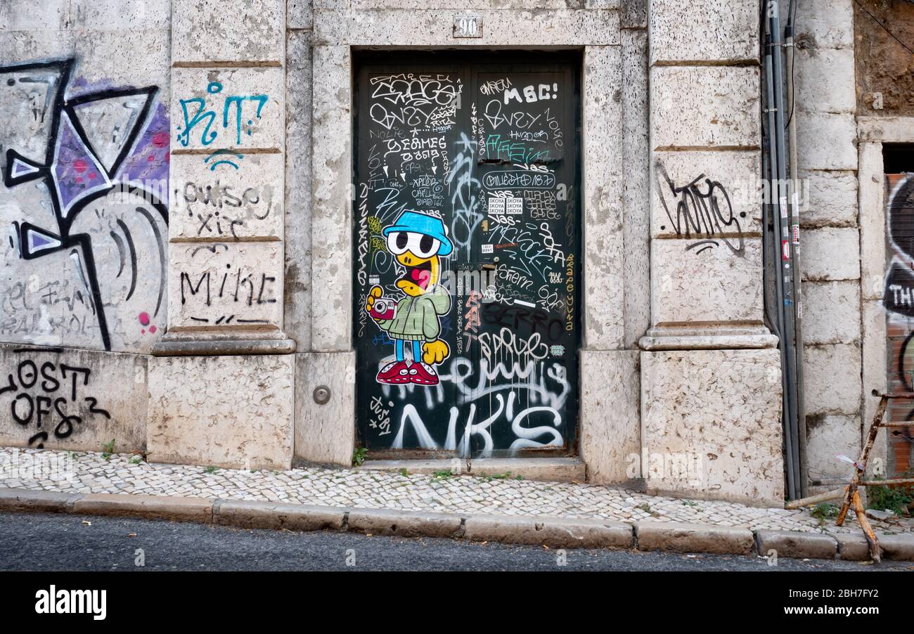 Kreative Graffiti und Tags schmücken die zerbröckelnde Pracht eines typischen Seiteneingangs zu einer Lissabon-Wohnung in Portugal. Stockfoto