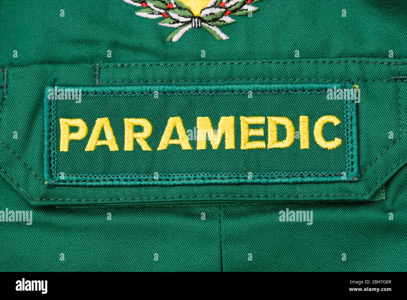 Nahaufnahme eines britischen SANITÄTER-Abzeichen, das auf ein grünes Sanitäter-Hemd genäht ist. Stockfoto
