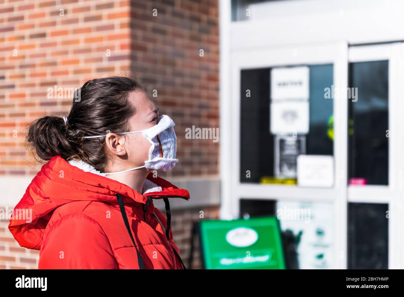 Soziale Distanzierung von Menschen warten in der Schlange stehen von Lebensmittelgeschäft Eingang mit Frau in hausgemachten Ofen Filter Maske und Rahmen während Corona Stockfoto