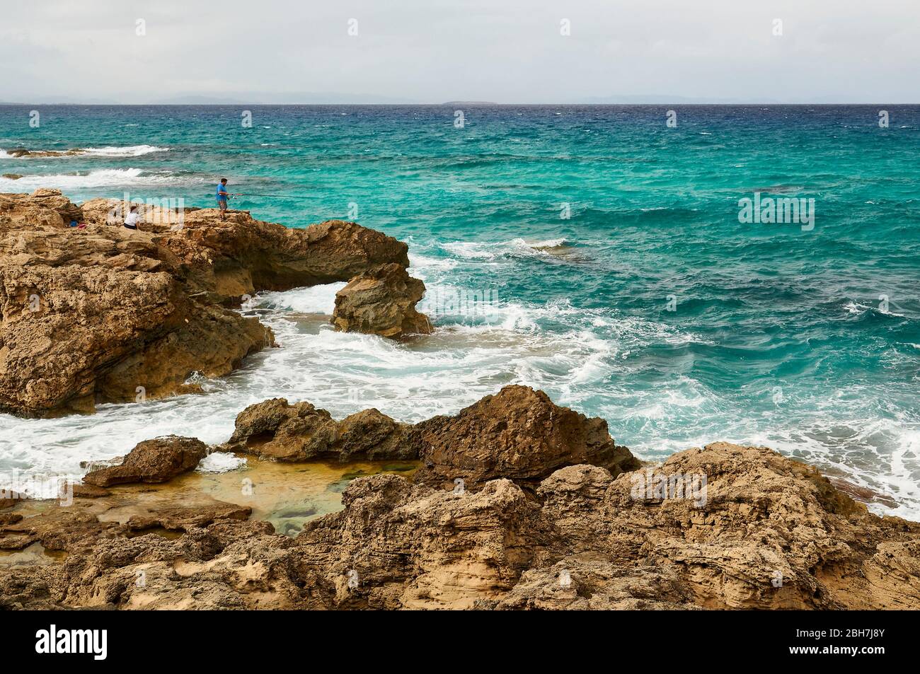 Fischer auf den Felsen an der Küste von Es Carnatge mit blauem rauem Wasser bei Es Caló (Formentera, Pityuses, Balearen, Mittelmeer, Spanien) Stockfoto