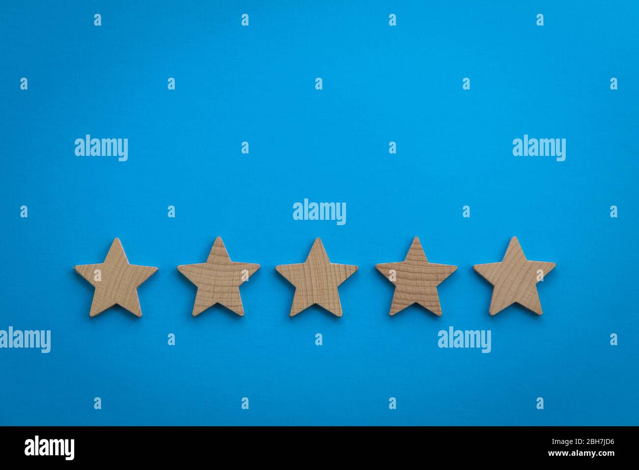 Fünf Sterne Bewertungskonzept mit Holzsternen auf blauem Papier Hintergrund Stockfoto