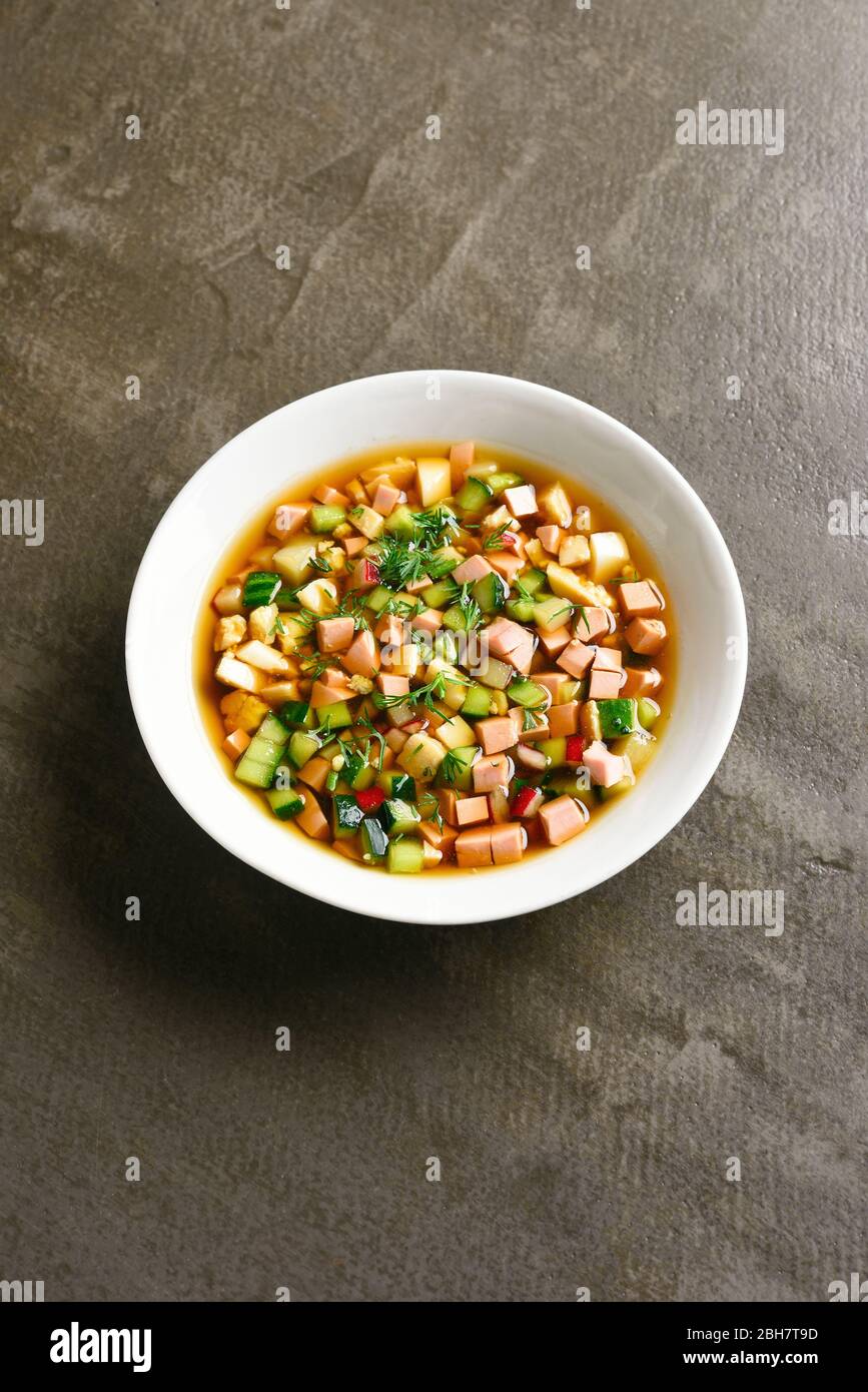 Traditionelle kalte Okroshka Suppe mit Wurst, Gemüse und Kvass auf braunem Hintergrund mit freiem Text Raum. Leckeres Sommergericht zum Abendessen. Stockfoto