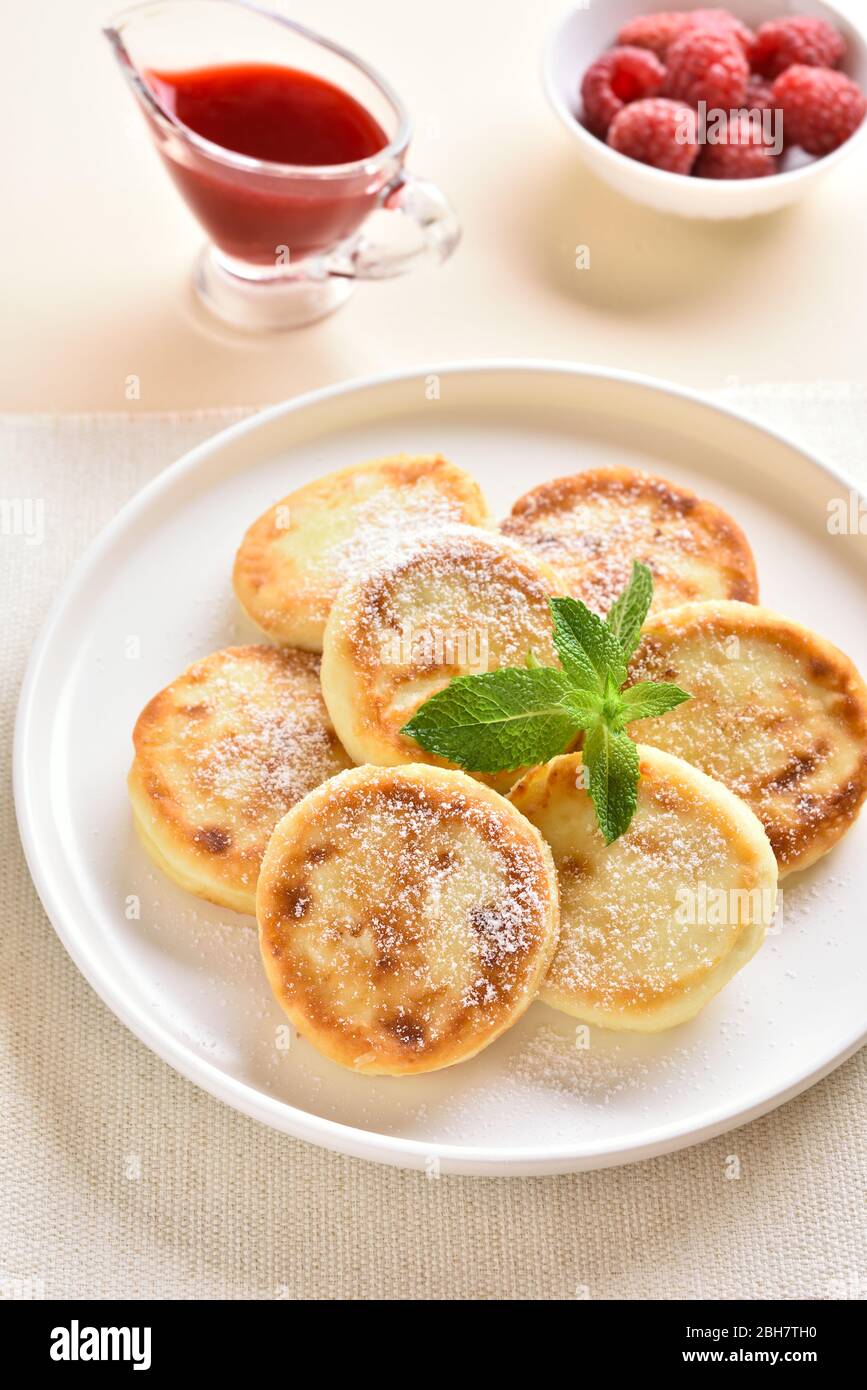 Nahaufnahme von Käsekuchen mit frischen Himbeeren auf dem Teller über hellem Steingrund. Stockfoto