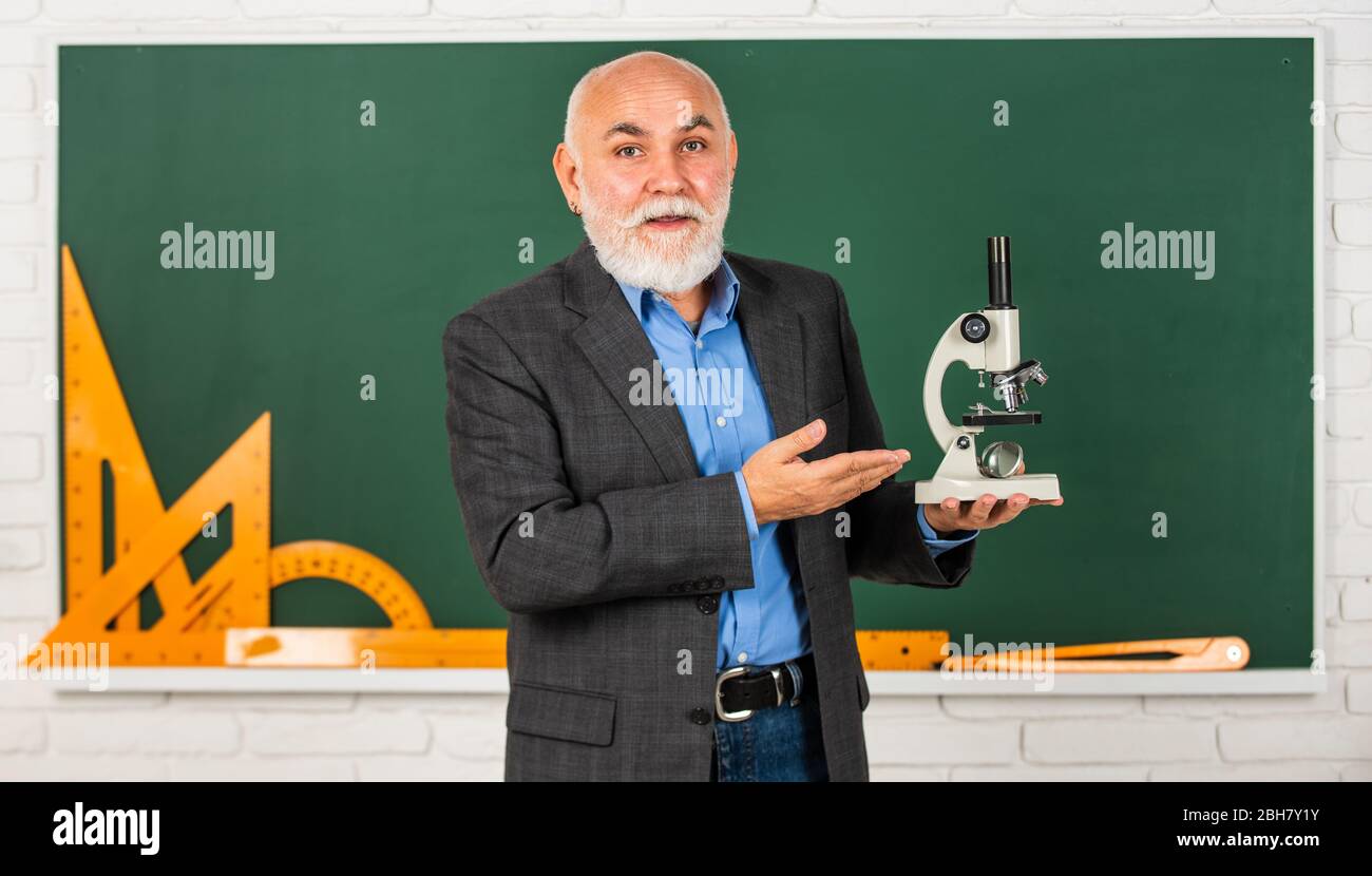 Heilung entdecken. Wissenschaftliche Experimente im Labor. Biologie Schule Laborausrüstung. Mann im Klassenzimmer mit mathematischen Werkzeugen an der Tafel. Senior Lehrer verwenden Mikroskop. Chemie im Schullabor. Stockfoto