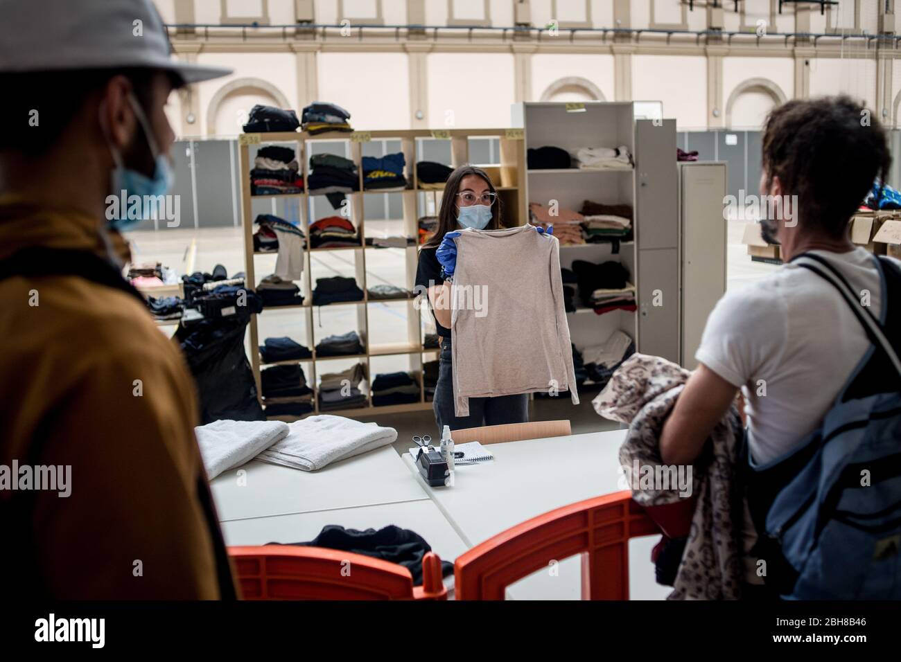 24. April 2020, Barcelona, Katalonien, Spanien - die Sozialarbeiterin Anna hält ein T-Shirt an einem Lebensmittel- und Bekleidungsverteilungsort in einem Sportkomplex von Barcelona, um die Bevölkerung mit wirtschaftlichen Problemen aufgrund der Pandemiekrise zu unterstützen. Spanien schlägt einen 1.5 Billionen Euro schweren Coronavirus-Rückgewinnungsfonds vor, der durch die unbefristete EU-Verschuldung finanziert wird. Die Europäische Union wird einen Rückgewinnungsfonds einrichten, der verschiedenen Ländern helfen soll, aus der Wirtschaftskrise, die durch die Coronavirus-Pandemie verursacht wurde, herauszukommen. Quelle: Jordi Boixareu/Alamy Live News Stockfoto