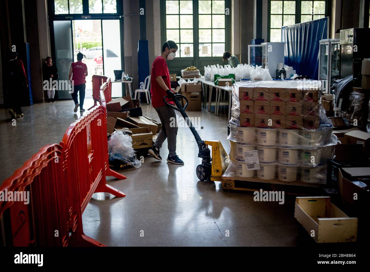 24. April 2020, Barcelona, Katalonien, Spanien - EIN Sozialarbeiter transportiert eine Palette an einem Lebensmittel- und Bekleidungsverteilungspunkt in einem Sportkomplex von Barcelona, um die Bevölkerung mit wirtschaftlichen Problemen aufgrund der Pandemiekrise zu unterstützen. Spanien schlägt einen 1.5 Billionen Euro schweren Coronavirus-Rückgewinnungsfonds vor, der durch die unbefristete EU-Verschuldung finanziert wird. Die Europäische Union wird einen Rückgewinnungsfonds einrichten, der verschiedenen Ländern helfen soll, aus der Wirtschaftskrise, die durch die Coronavirus-Pandemie verursacht wurde, herauszukommen. Quelle: Jordi Boixareu/Alamy Live News Stockfoto