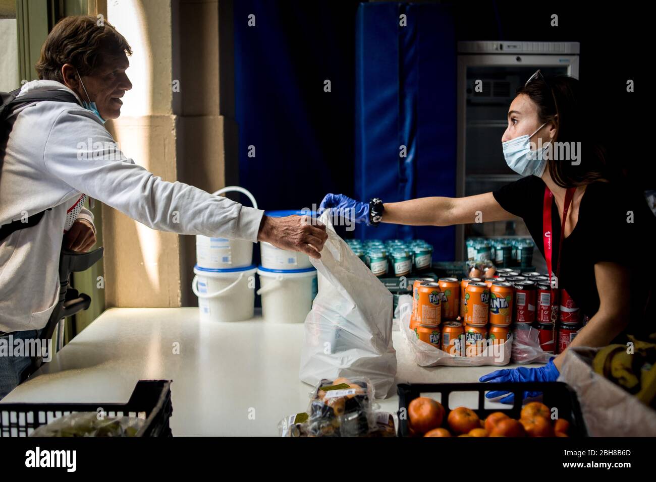 24. April 2020, Barcelona, Katalonien, Spanien - die Sozialarbeiterin Anna (R) liefert eine Tasche mit einem Menü an einer Lebensmittelverteilungsstelle in einem Sportkomplex von Barcelona, um die Bevölkerung mit wirtschaftlichen Problemen aufgrund der Pandemiekrise zu unterstützen. Spanien schlägt einen 1.5 Billionen Euro schweren Coronavirus-Rückgewinnungsfonds vor, der durch die unbefristete EU-Verschuldung finanziert wird. Die Europäische Union wird einen Rückgewinnungsfonds einrichten, der verschiedenen Ländern helfen soll, aus der Wirtschaftskrise, die durch die Coronavirus-Pandemie verursacht wurde, herauszukommen. Quelle: Jordi Boixareu/Alamy Live News Stockfoto