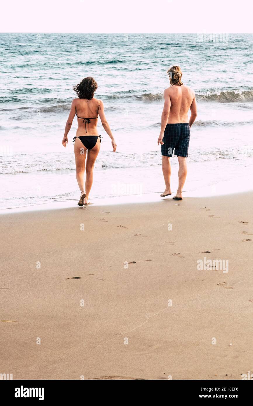 Junges Paar von hinten gesehen zu Fuß zum Wasser während eines Urlaubs. Meer und Strand und schöne Menschen - Beziehung und Liebe für Mann und Frau im Urlaub - Sand und Wellen Lebensstil Stockfoto