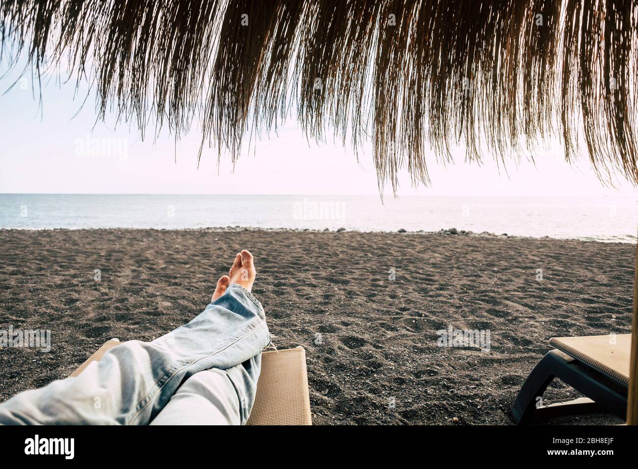 Mann Füße Sicht, während allein ruhen und entspannen am Strand mit Meer vor dem Ende des Sandes. Stockfoto