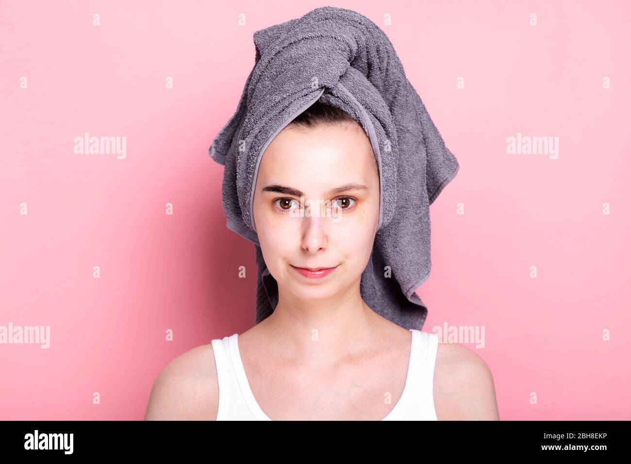 Junge Frau mit Handtuch auf dem Kopf malt ihre Augenbrauen auf sich. Konzept Spa Tag zu Hause und in Quarantäne Stockfoto