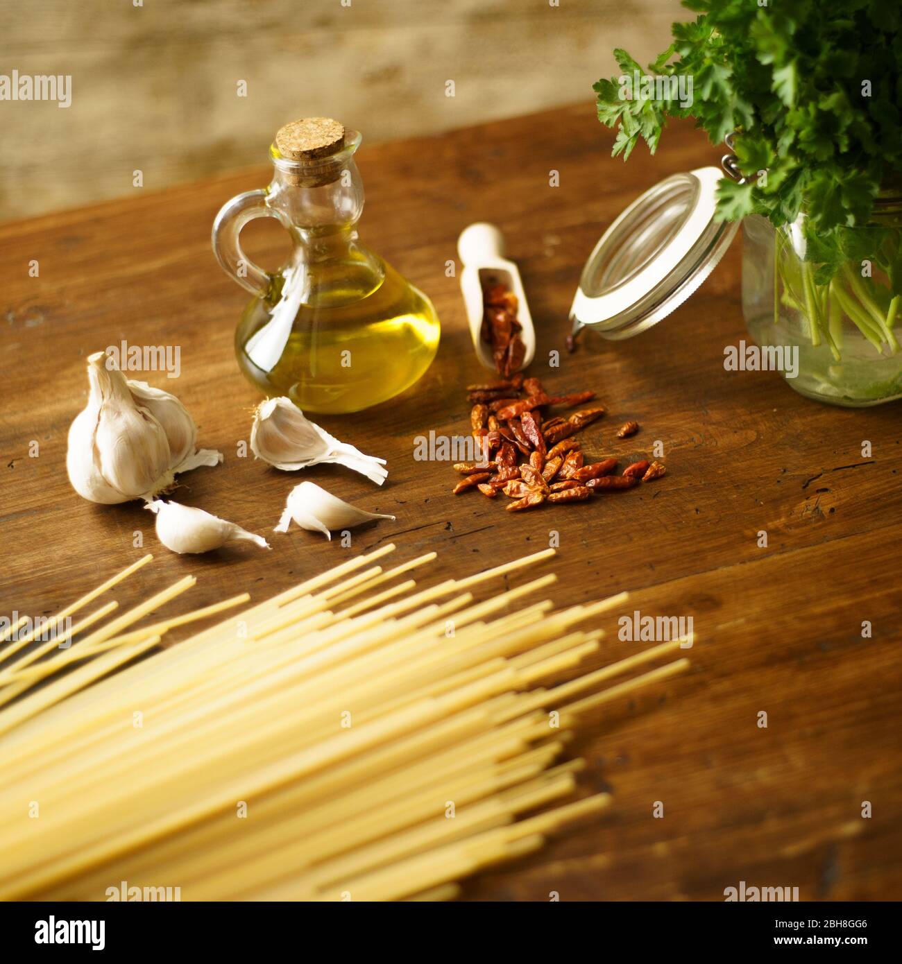 Niedrige Winkelansicht des typisch italienischen Rezept Spaghetti aglio olio e peperoncino (Knoblauch, Öl und Paprika) Zutaten mit einem Glas mit Sprigs Stockfoto