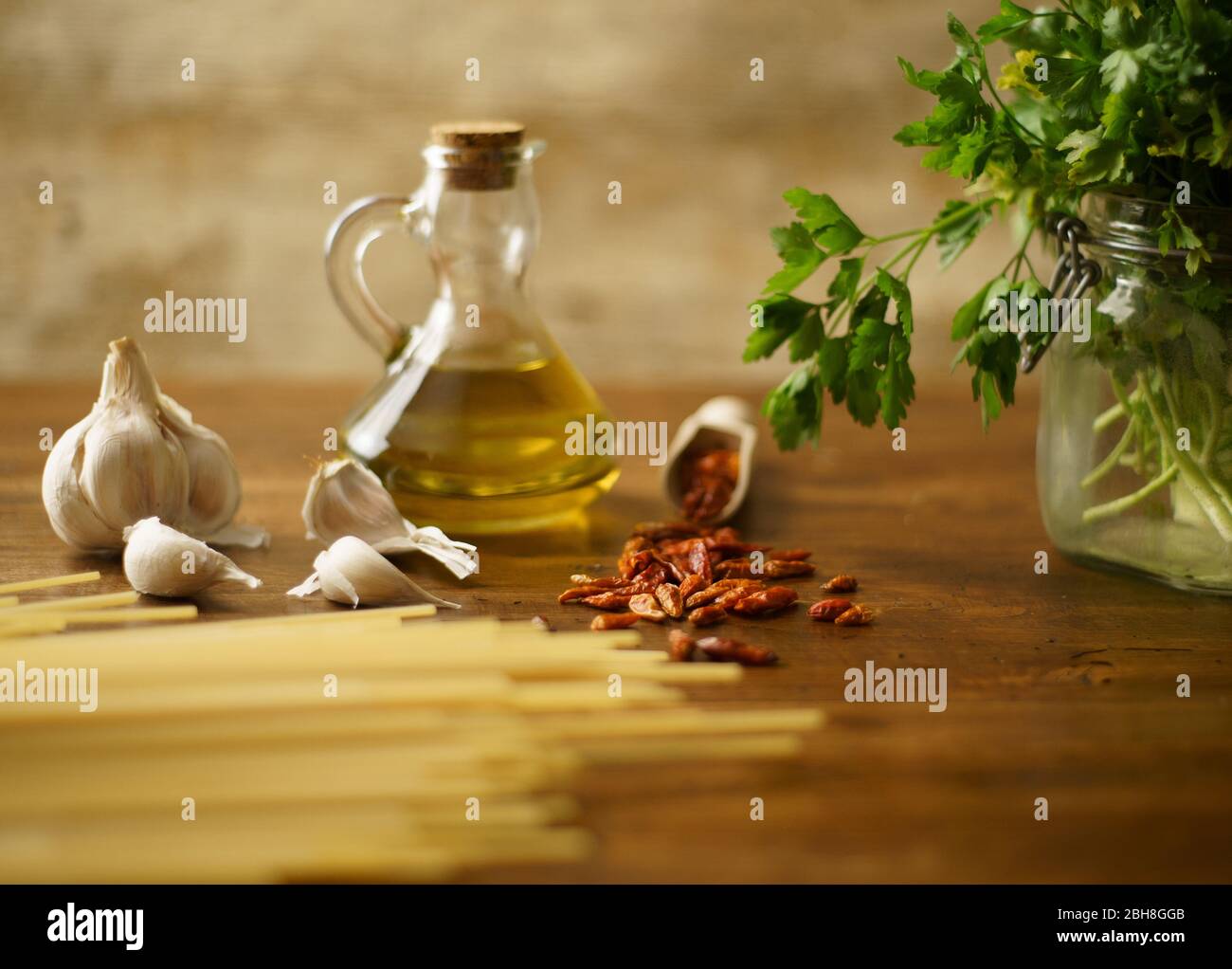 Niedrige Winkelansicht des typisch italienischen Rezept Spaghetti aglio olio e peperoncino (Knoblauch, Öl und Paprika) Zutaten mit einem Glas mit Sprigs Stockfoto