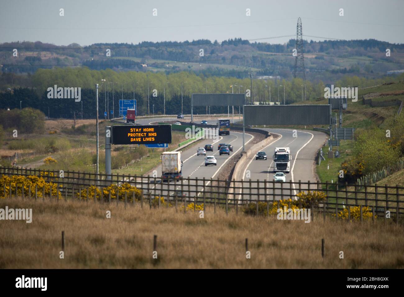 Cumbernauld, Großbritannien. April 2020. Im Bild: Straßenschilder entlang der Autobahn M80, die lauteten: „BLEIB ZUHAUSE, SCHÜTZE NHS, RETTE LEBEN“ die britische Regierung hat eine längere Stillegungen aller großen Städte Großbritanniens angeordnet und die Menschen zu Hause bleiben lassen, obwohl einige Leute die Botschaft der Regierung ignorieren wollen. Bis heute hat die Coronavirus (COVID-19) Pandemie weltweit über 2.74 Millionen Menschen infiziert, und in Großbritannien 143,464 infiziert und 19,506 getötet. Quelle: Colin Fisher/Alamy Live News Stockfoto