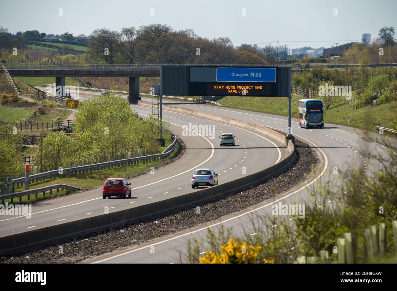 Cumbernauld, Großbritannien. April 2020. Im Bild: Straßenschilder entlang der Autobahn M80, die lauteten: „BLEIB ZUHAUSE, SCHÜTZE NHS, RETTE LEBEN“ die britische Regierung hat eine längere Stillegungen aller großen Städte Großbritanniens angeordnet und die Menschen zu Hause bleiben lassen, obwohl einige Leute die Botschaft der Regierung ignorieren wollen. Bis heute hat die Coronavirus (COVID-19) Pandemie weltweit über 2.74 Millionen Menschen infiziert, und in Großbritannien 143,464 infiziert und 19,506 getötet. Quelle: Colin Fisher/Alamy Live News Stockfoto