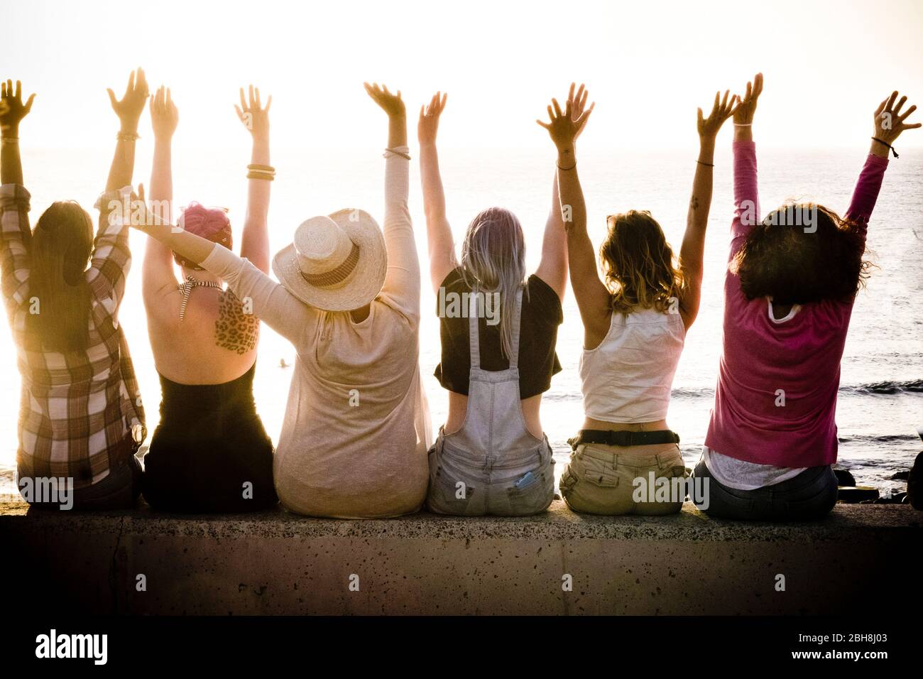 Rückansicht der Gruppe von Frauen kaukasischen Freunde genießen bei Sonnenuntergang mit Meer im Hintergrund - Erfolg und Zufriedenheit Konzept für nette Menschen zusammen mit Freude - Freundschaft und Urlaub Stockfoto