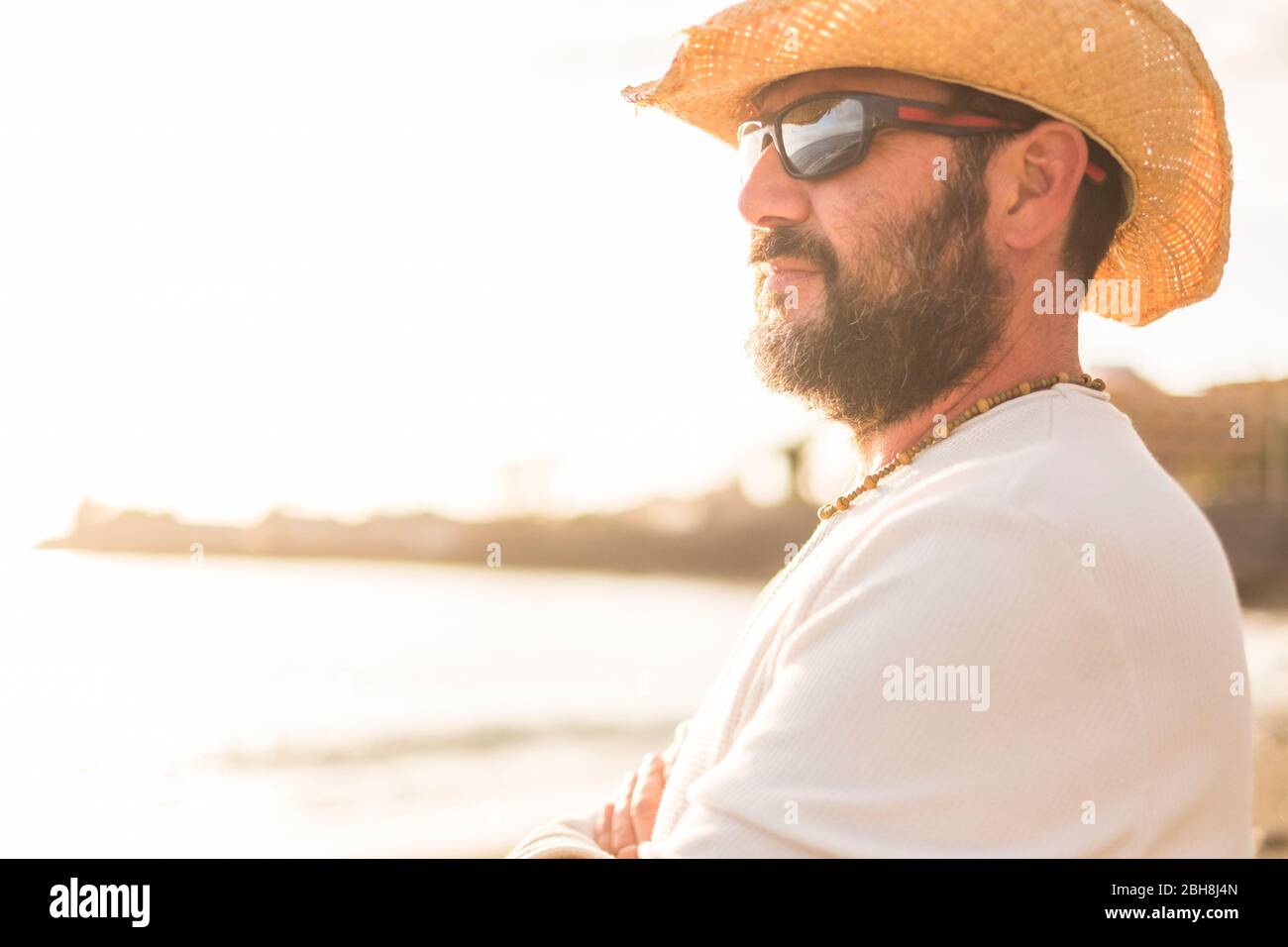 Mitte Alter 45 Jahre alten weißen Mann in Urlaub am Horizont mit einem golde Sonnenuntergang im Hintergrund. mit Sonnenbrille und Sommer Kleidung Stockfoto