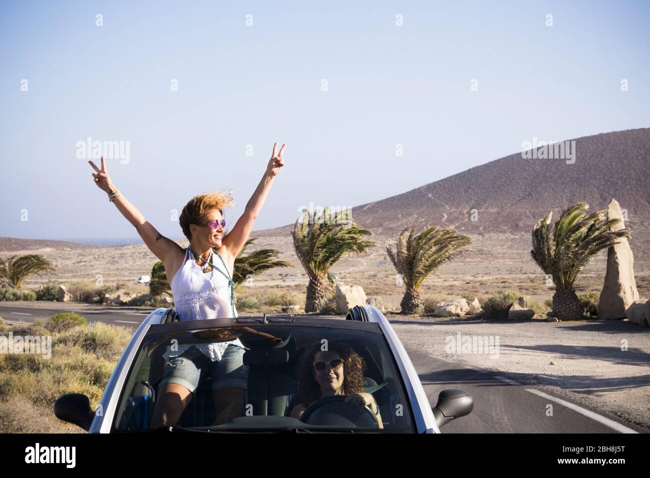 Ein Paar glückliche Frau genießen die Reise mit dem Auto reisen - fahren und stehen außerhalb des Daches mit Erfolg und Glück Pose - Urlaub im Freien tropischen Ort für fröhliche Menschen Stockfoto Ein Paar glückliche Frau genießen die Reise mit dem Auto reisen - fahren und stehen außerhalb des Daches mit Erfolg und Glück Pose - Urlaub im Freien tropischen Ort für fröhliche Menschen Stockfoto
