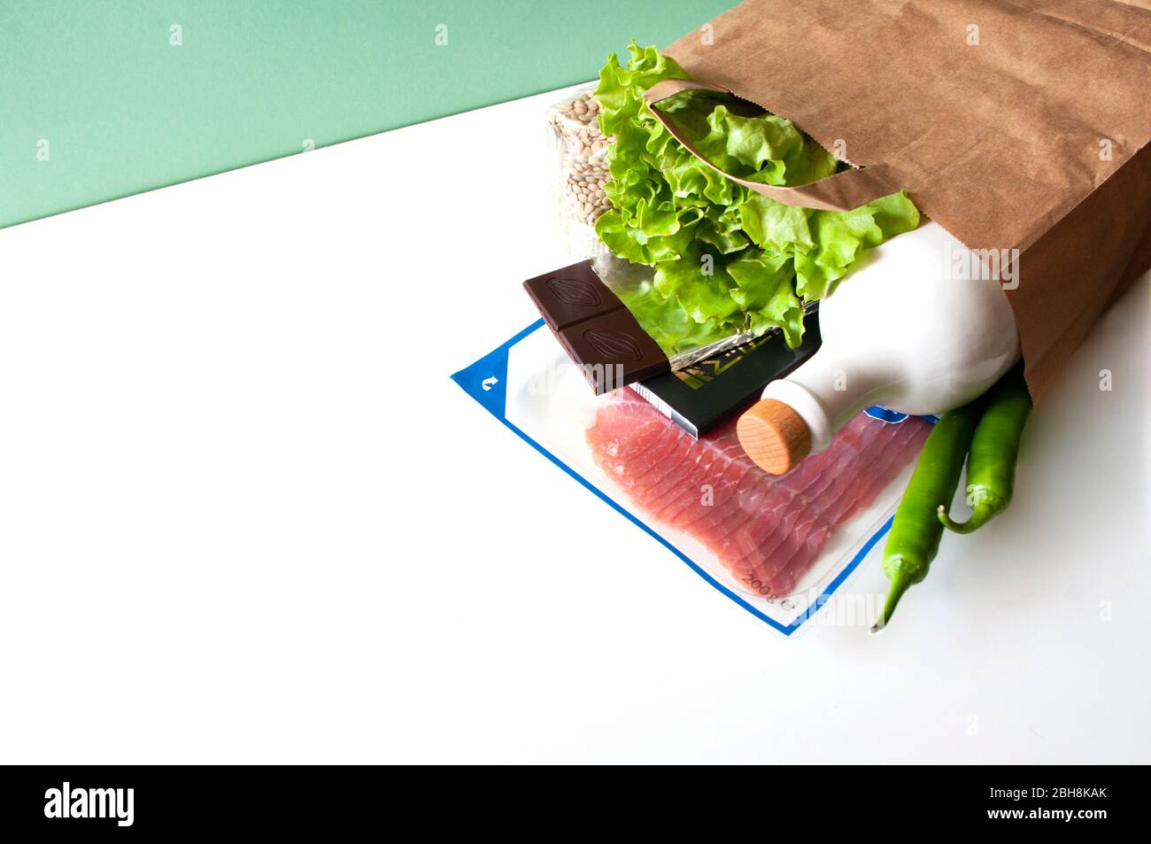 Lieferung von Lebensmitteln, kontaktlos, Einkaufen, Lebensmittelspende. Papiertüte Speck, Schokolade, grüne Chili, Salat, Olivenöl Botle. Stockfoto