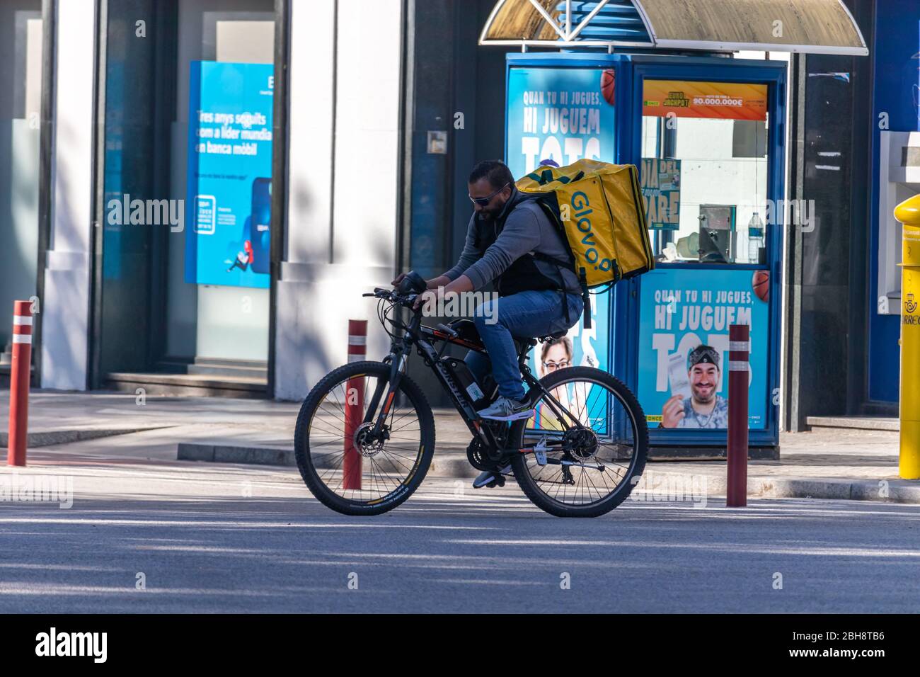 Barcelona, Spanien. April 2020. Glovo Deliveryman, der während des kovidischen Alarmzustands durch die leeren Straßen Barcelonas radelt Stockfoto