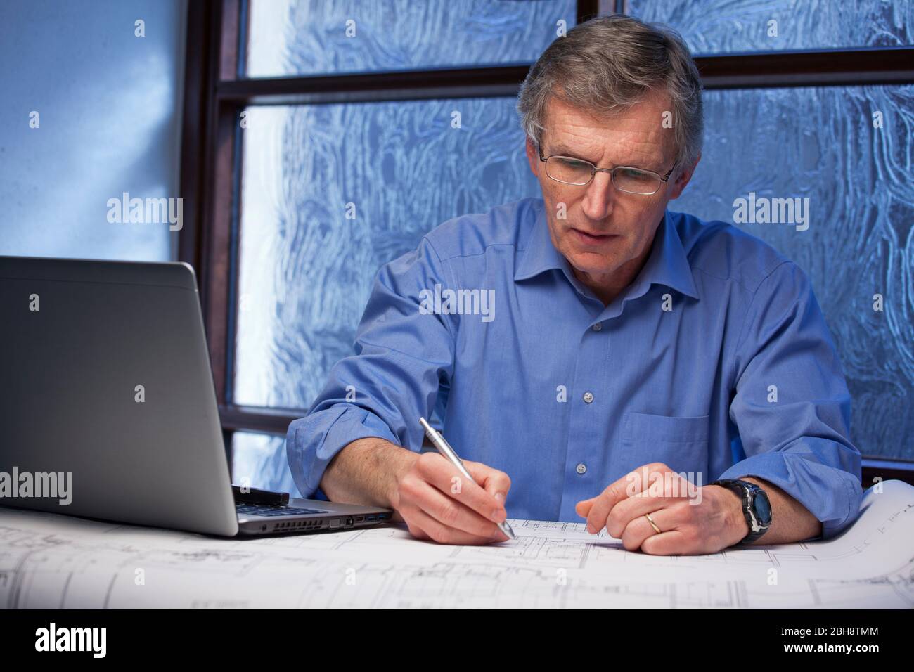 Reife Architekt oder Ingenieur arbeiten von zu Hause aus an einem Schreibtisch mit Laptop ein Plan - konzentrieren Sie sich auf das Gesicht Stockfoto