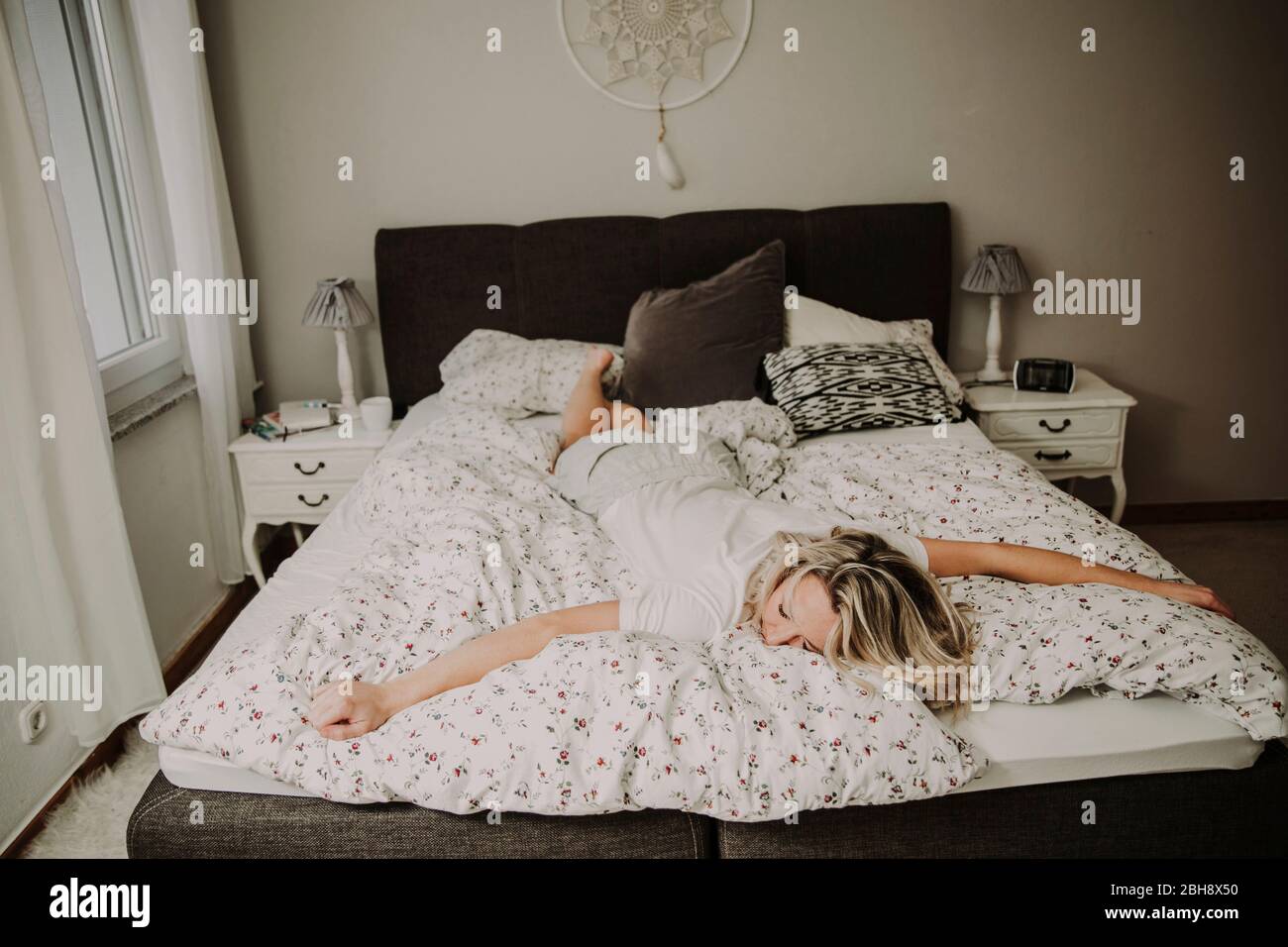 Frau liegt erschopft im Bett Stockfoto