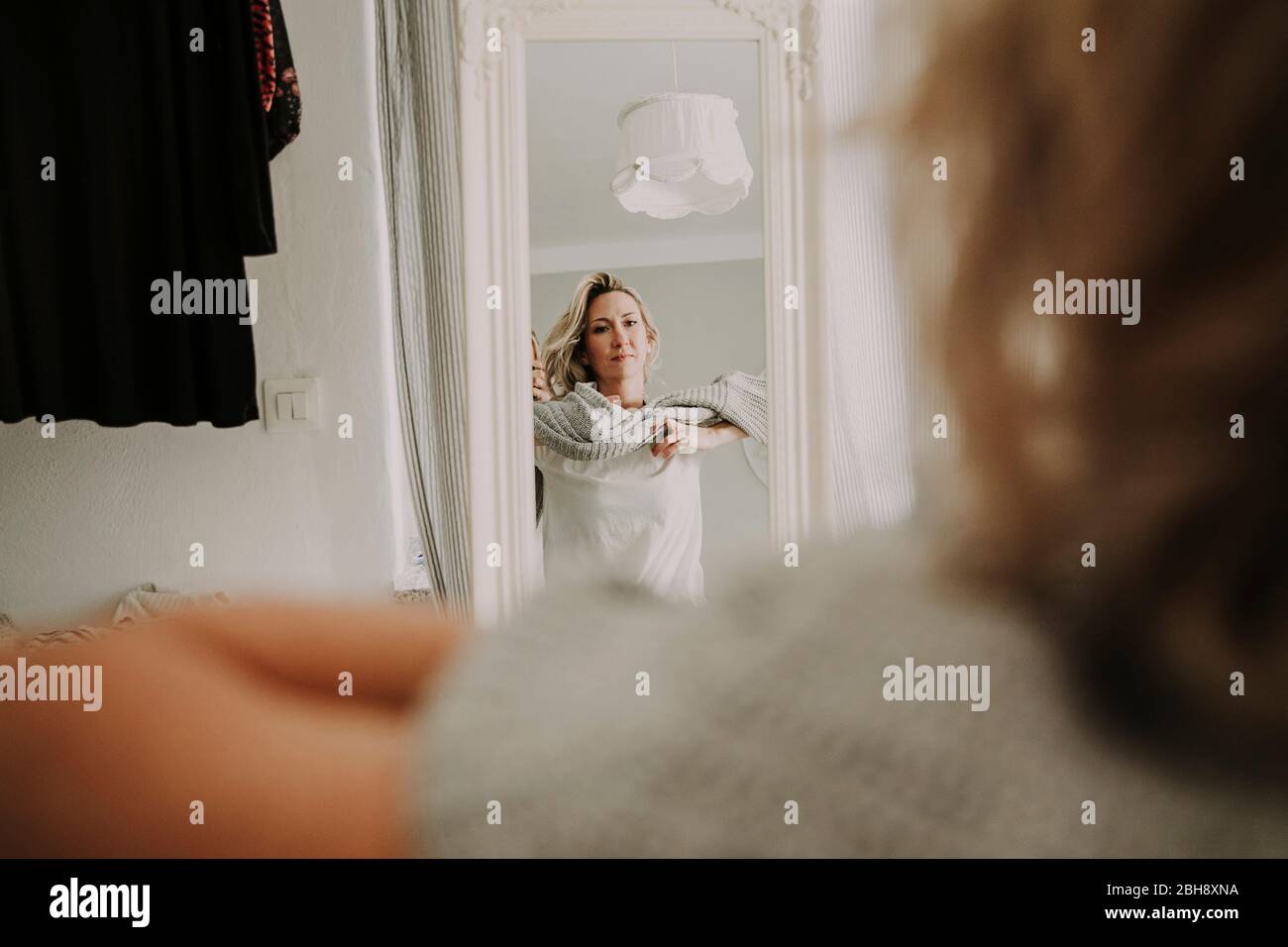Frau steht vor dem Spiegel, bekleidet Stockfoto