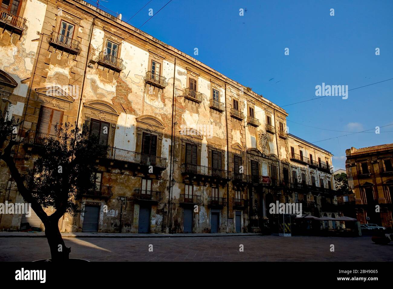 Palermo, Altstadt, piazza mit altem langgestrecktem Gebäude, das im Abendlicht renoviert werden soll, abblätternder Putz Stockfoto