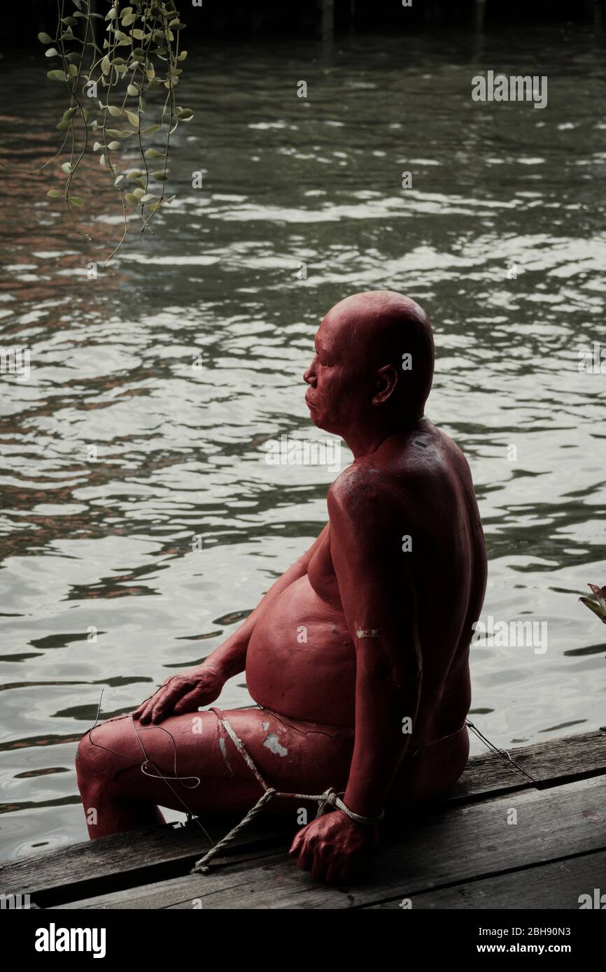 Rot gemalte Steinfigur auf Seitenarm eines Kanals von Bangkok Stockfoto