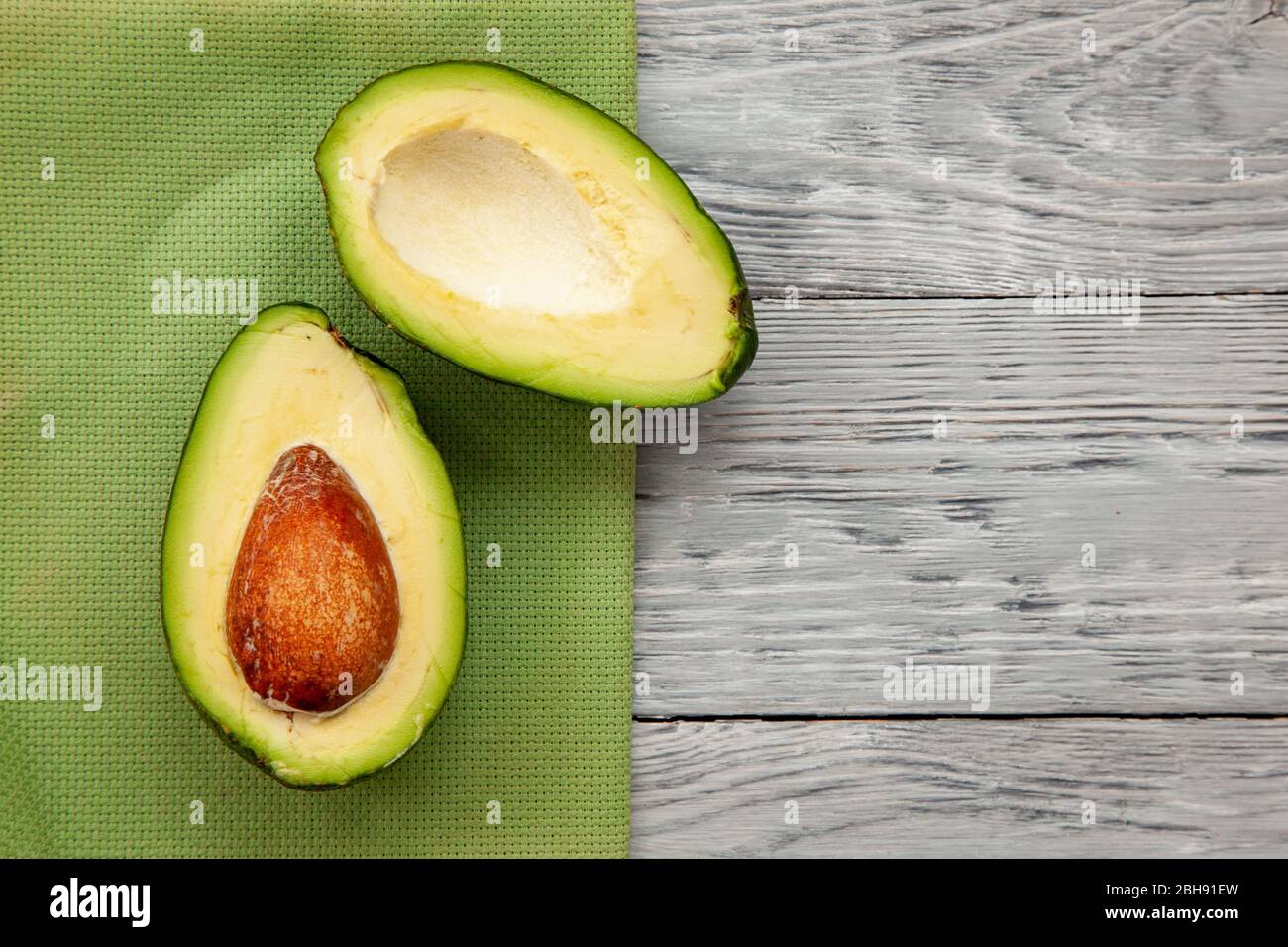 Zwei Hälften reifer Avocado auf einem hölzernen Hintergrund. Ansicht von oben und Kopie des Raums Stockfoto