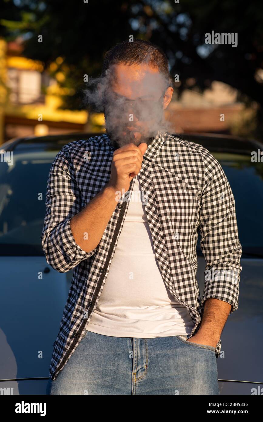 Junger Mann steht neben dem Auto beim Dampfen Stockfoto