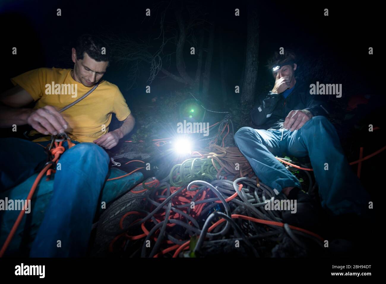Zwei Männer sitzen nach dem Aufstieg und organisieren im Dunkeln Kletterausrüstung Stockfoto